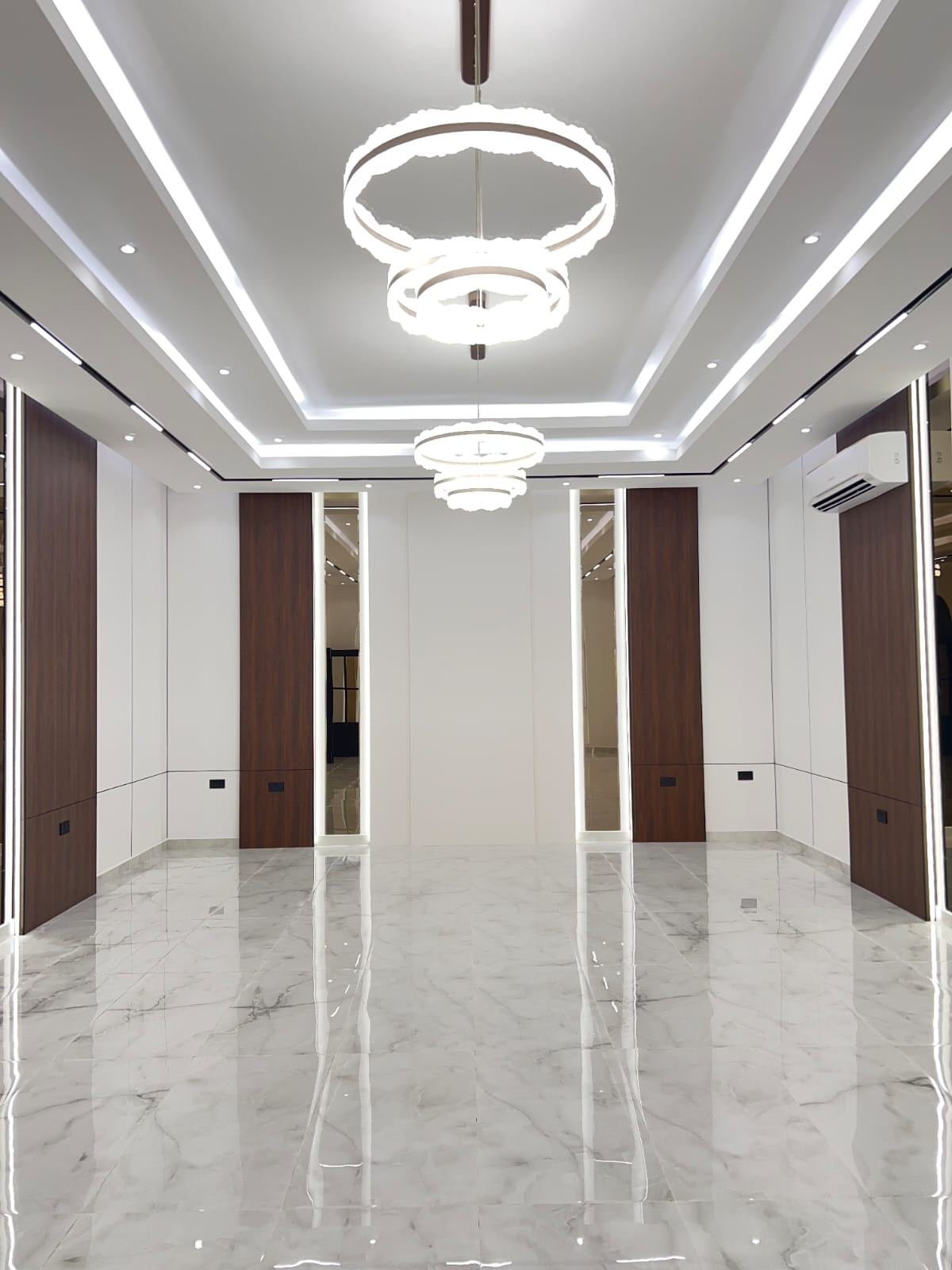 Hallway with walnut wall paneling and ring pendant lighting