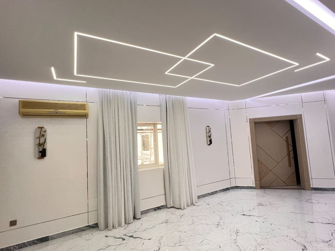 Geometric gypsum ceiling with recessed LED channel lighting above a marble floor