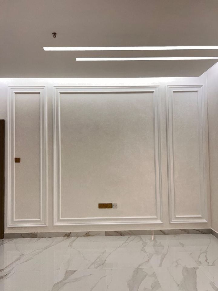 Moulded white wainscoting wall panels with recessed cove lighting