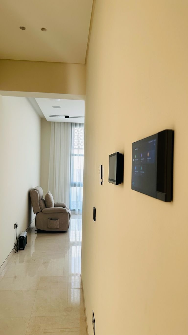 Wall-mounted touch control panels beside an accessible living room with a recliner chair
